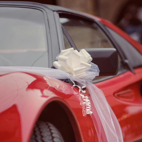 A close-up of a wedding bow on a beautiful red Italian sports car.