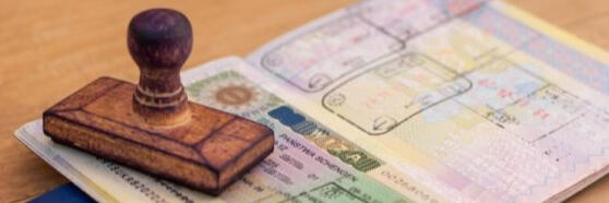 An open passport displaying a colorful stamp and a Schengen visa issued based on a sworn certified translation of vital records into Italian.